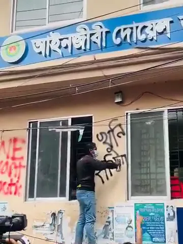 The student spray paints, "Murderer Hasina" on the wall. a large crowd cheers. This is yesterday at.